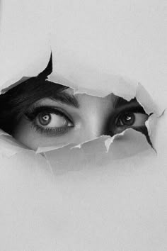 a black and white photo of a woman's face peeking through a hole in paper