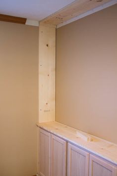 an unfinished room with wood paneling on the wall and cabinets in place for painting