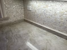 an empty kitchen with white tile on the walls and floor, in front of a window