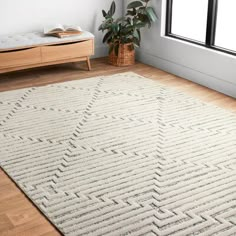 a large white rug in the corner of a room with a wooden floor and window