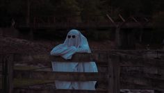 a ghostly ghost sitting on top of a wooden fence