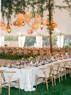 an outdoor tent with tables and chairs set up for a wedding reception in the grass