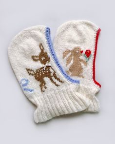 two white mittens with reindeers on them, one is red and the other is blue