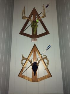 two deer heads mounted to the side of a wall next to arrows and an arrow