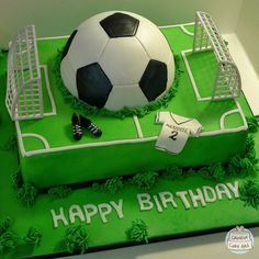 a birthday cake with a soccer ball and goal on the top is decorated in green frosting