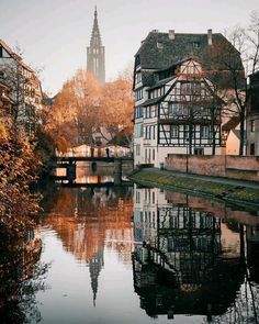 a river running through a small town with tall buildings on both sides and a clock tower in the background