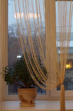 a potted plant sitting on top of a window sill next to a curtain