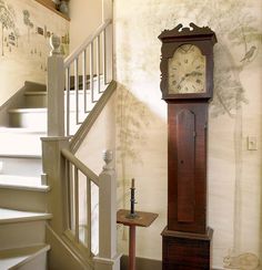 a grandfather clock sitting in the corner of a room next to a stair case and railing