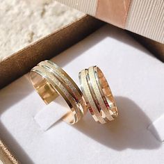 two gold rings sitting in a box next to each other