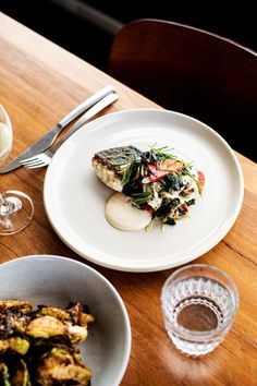 two plates with food and wine on a wooden table