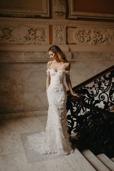 a woman in a wedding dress standing on the stairs with her hand on her hip