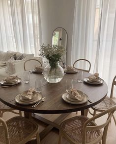 a dining room table set with place settings and plates on it, in front of a white couch