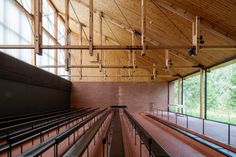 an empty auditorium with rows of seats and railings in front of large windows that overlook trees