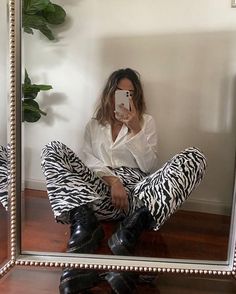 a woman sitting on the floor in front of a mirror taking a selfie with her cell phone