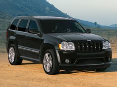 a black jeep parked on the side of a dirt road