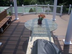 a glass table and bench on a wooden deck