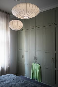 a bed room with a neatly made bed and two lights hanging from it's ceiling