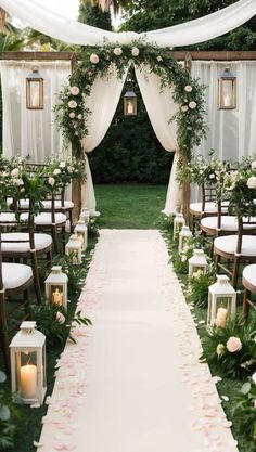 the aisle is lined with white and pink flowers, greenery, candles and lanterns