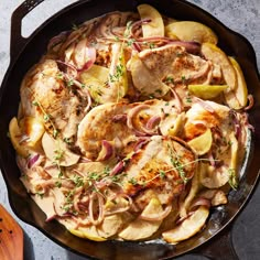 a skillet filled with chicken, potatoes and onions