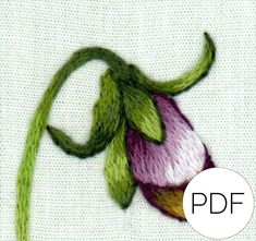 a close up of a flower on a piece of cloth with green and purple thread