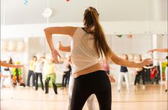 a group of young women dancing in a dance studio with one woman holding her arms out to the side