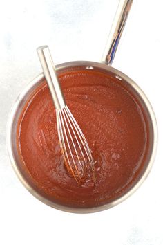 a whisk is in a bowl with sauce