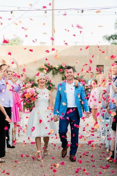 a bride and groom walk down the aisle as confetti falls around them