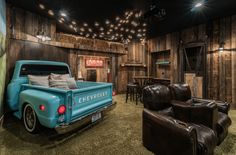 an old fashioned truck is parked in a room with wood paneling and leather furniture