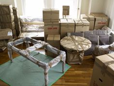 a room filled with boxes and furniture on top of a hard wood floor next to a window