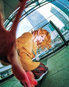 a young woman riding a skateboard on top of a cement floor next to tall buildings