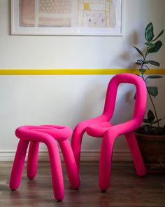 a pink chair and footstool sitting in front of a painting on the wall