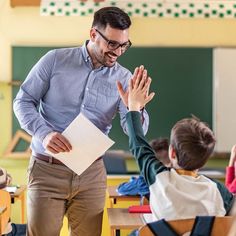 a man in glasses and a blue shirt is giving a high five to a young boy