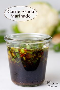 a jar filled with food sitting on top of a white table next to some vegetables