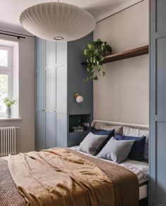 a bedroom with a bed, shelves and plants on the wall above it's headboard