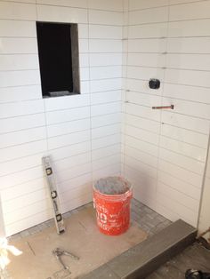 a bucket sitting on top of a floor next to a hole in the wall that is being built