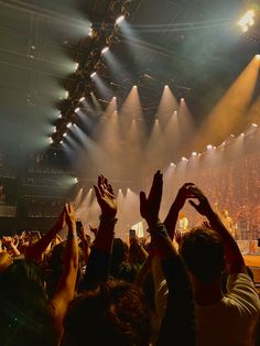 a crowd of people at a concert with their hands in the air and lights on