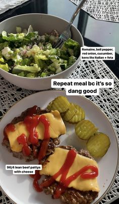 a white plate topped with meat covered in ketchup next to a bowl of salad