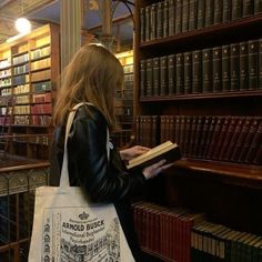 a woman holding a book in front of a library full of books