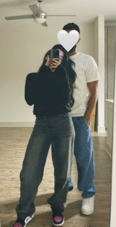 a man and woman standing in front of a mirror with hearts on their foreheads