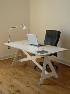 a laptop computer sitting on top of a white desk next to a black leather chair