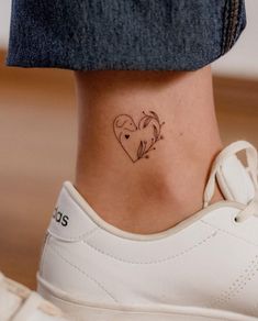 a woman's ankle with a small heart tattoo on her left side ribcage