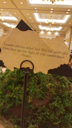 a sign that is sitting on top of a plant in a glass bowl with moss