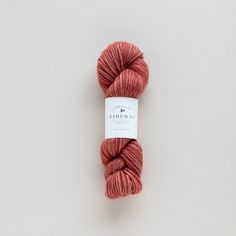 a skein of red yarn sitting on top of a white surface with a tag