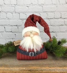 a santa clause figurine sitting on top of a wooden table next to greenery