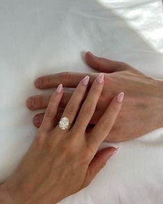 a woman's hand with a diamond ring on her left and a man's right hand