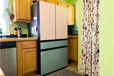 a kitchen with green walls and wooden cabinets in the corner, along with a curtained window