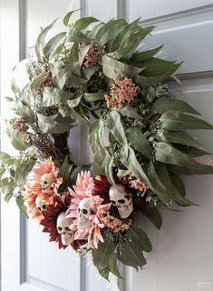 a wreath with flowers and skulls hanging on the front door