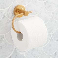 a roll of toilet paper is hanging on the wall next to a gold faucet