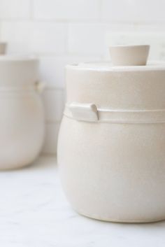 two white pots sitting on top of a counter