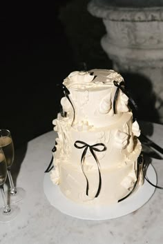 a three tiered wedding cake sitting on top of a table next to a glass of wine